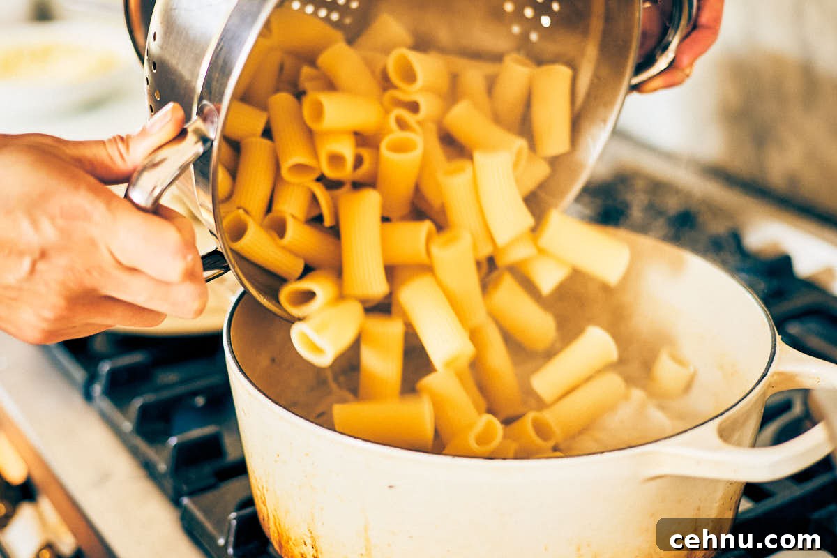 Cooked pasta being added to a pot of garlic herb sauce.