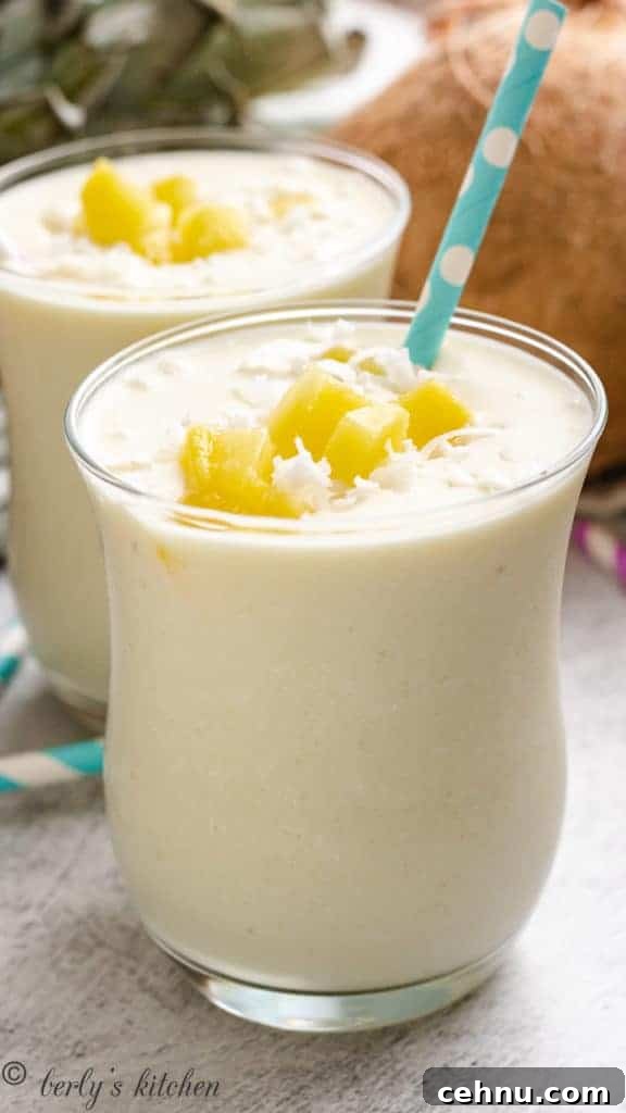 Two glasses with a tropical smoothie and blue and white straw.