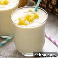 Two glasses of smoothie with pineapple and shredded coconut.