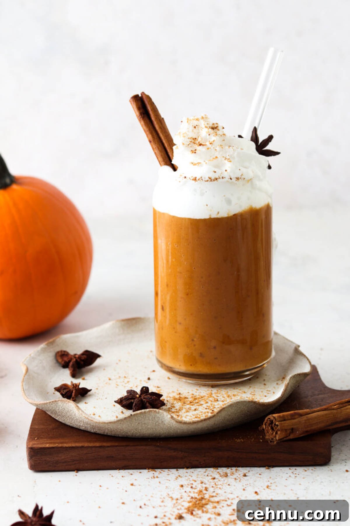 Dairy free pumpkin spice smoothie in a glass cup and topped with whipped cream and fresh spices.