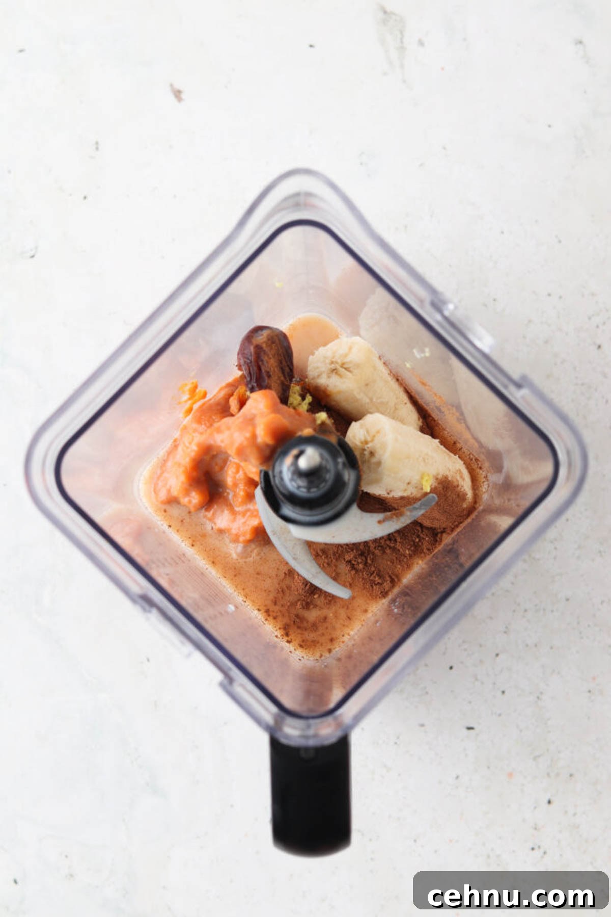 Dairy free pumpkin spice smoothie ingredients in a blender base unmixed.