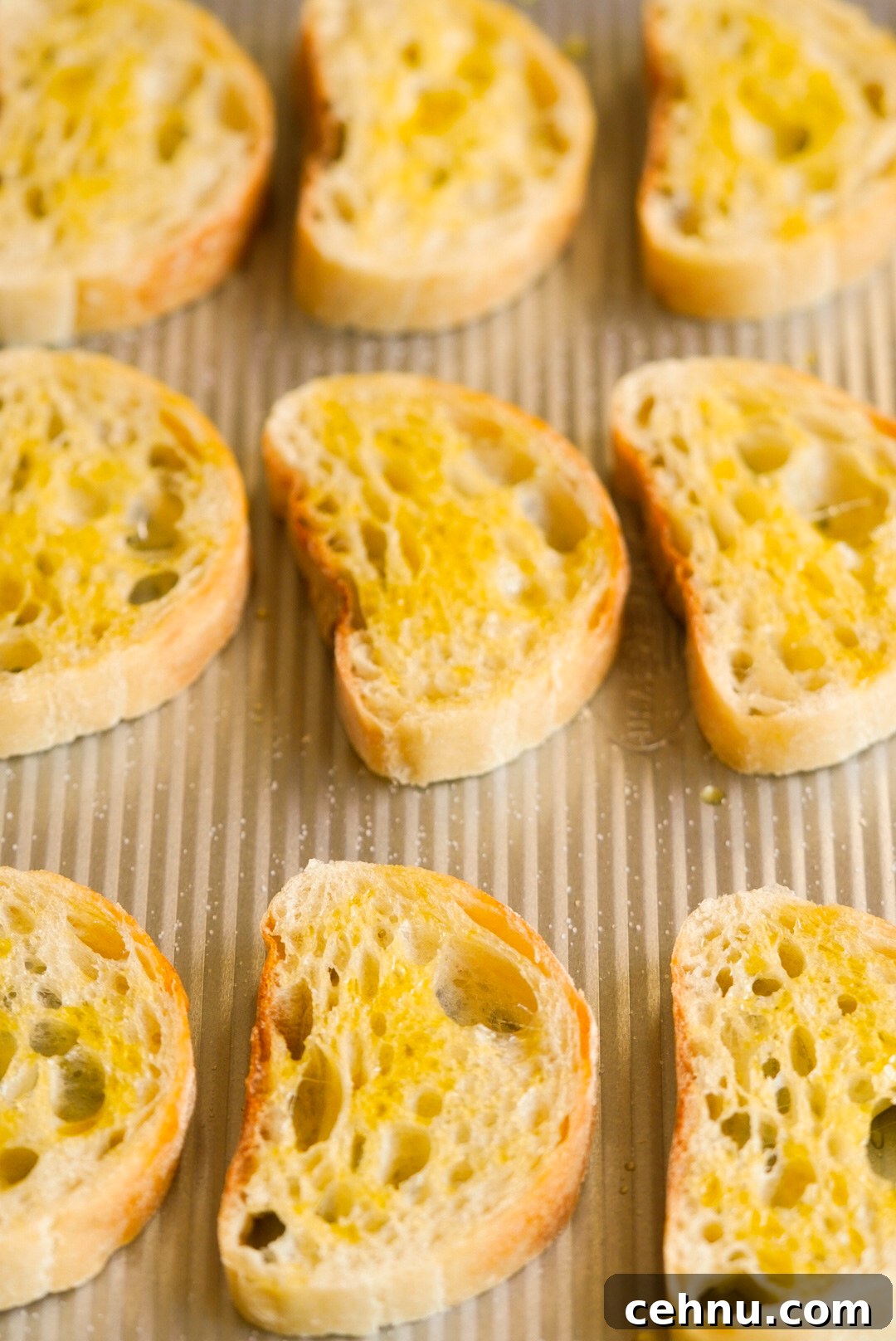 ciabatta slices topped with olive oil on a baking sheet