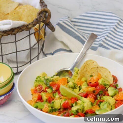 white bowl of mandarin guacamole with basket of tortilla chips