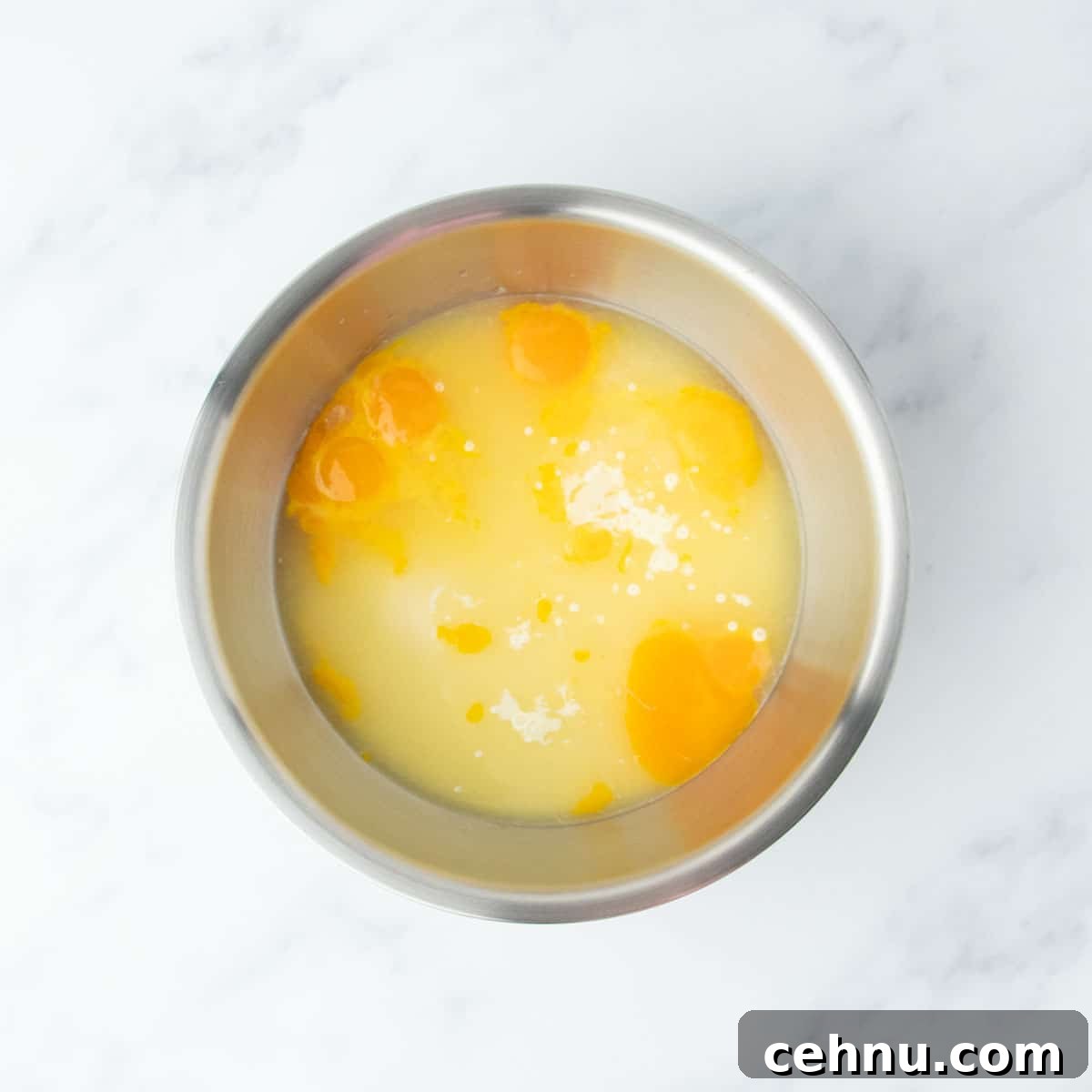 Top-down view of egg yolks and lemon juice added to the bowl with sweetened condensed milk.