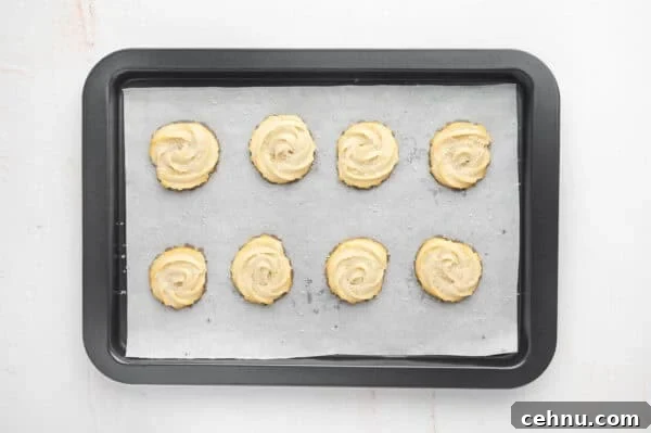 Classic Butter Cookies Recipe for Tea Time 11 Freshly baked butter cookies on a parchment lined baking sheet.