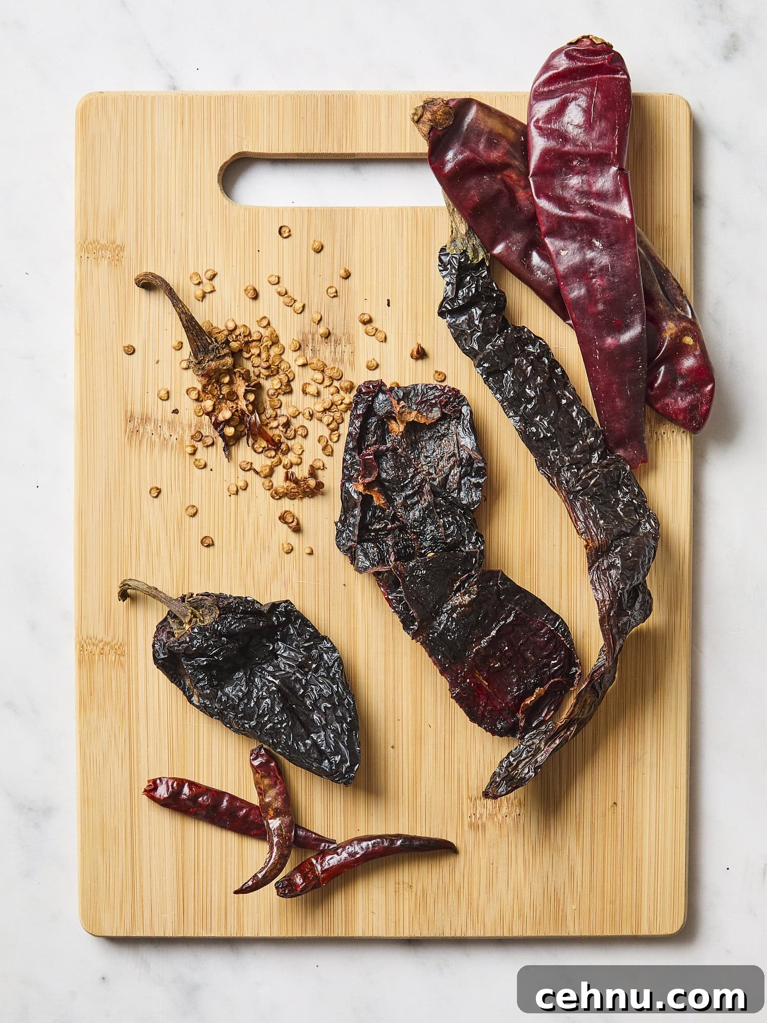 Cutting board with dried chiles with seeds removed.