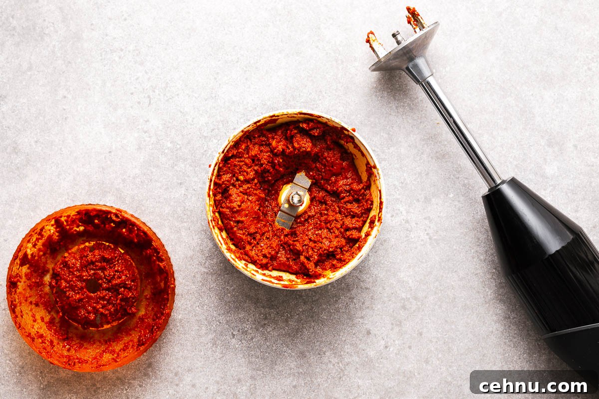 A bamix immersion blender with small food processor (spice grinder) attachment containing homemade Thai red curry paste.