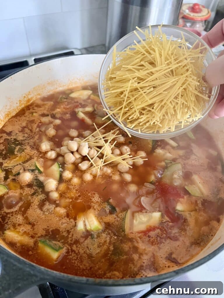 Adding broken pieces of cappellini pasta to soup.