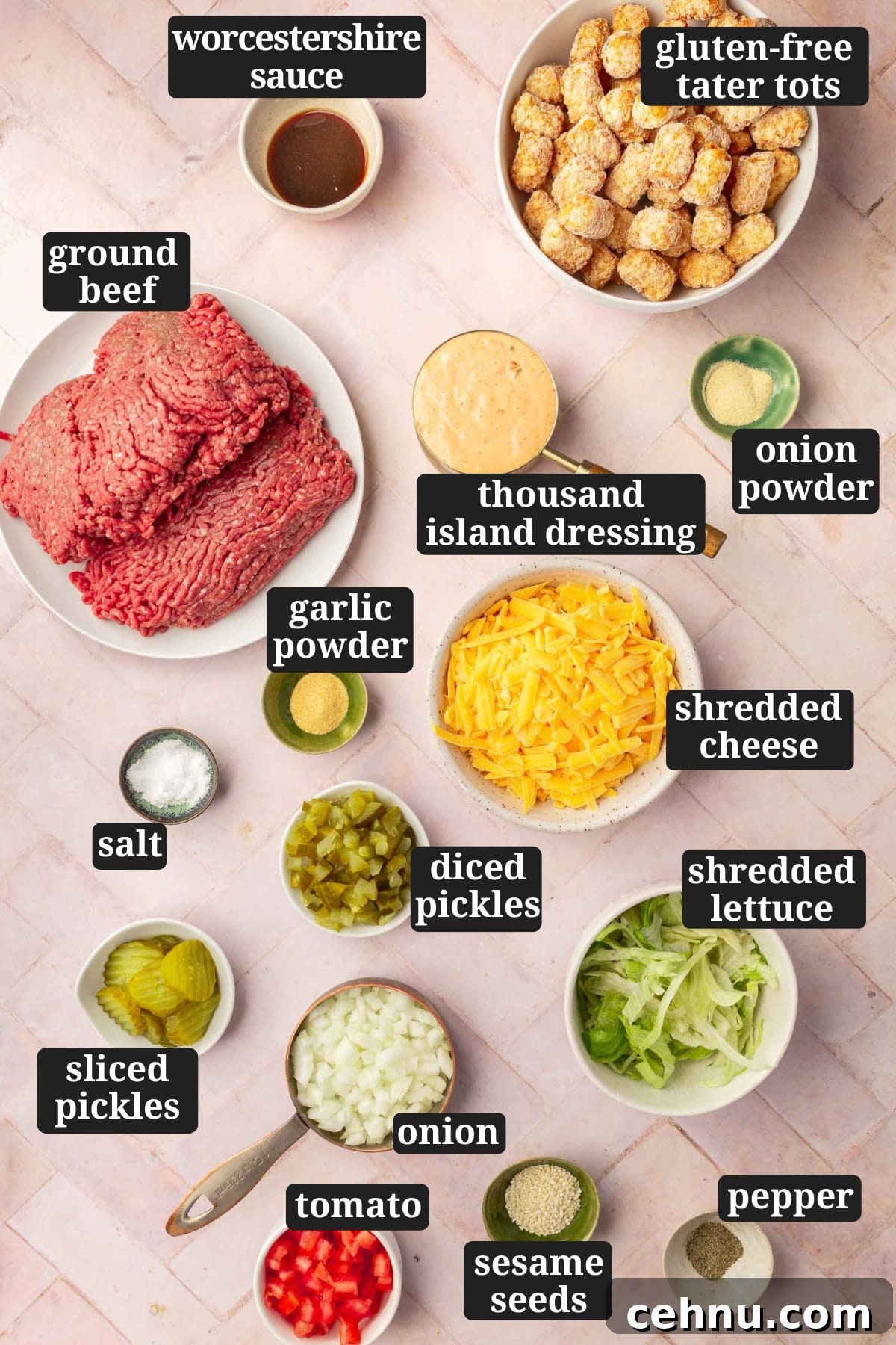 An overhead view of ingredients in bowls to make big mac tater tot casserole including worcestershire sauce, frozen tater tots, ground beef, thousand island dressing, garlic powder, onion powder, salt, shredded cheddar cheese, diced pickles, sliced pickles, onions, shredded lettuce, diced tomato, sesame seeds, and black pepper with text overlays over each ingredient.