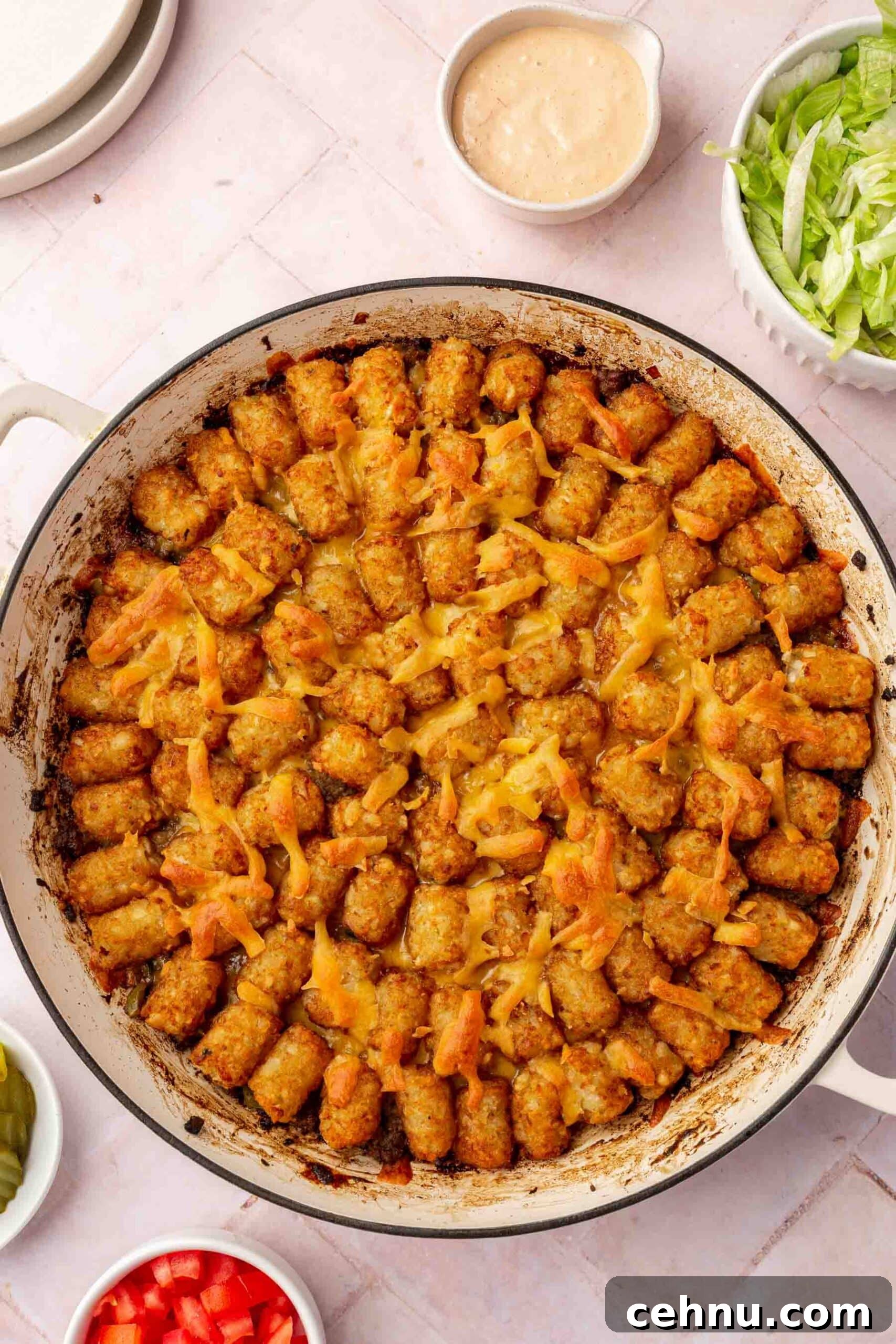A big mac tater tot casserole in a round white braising pan.