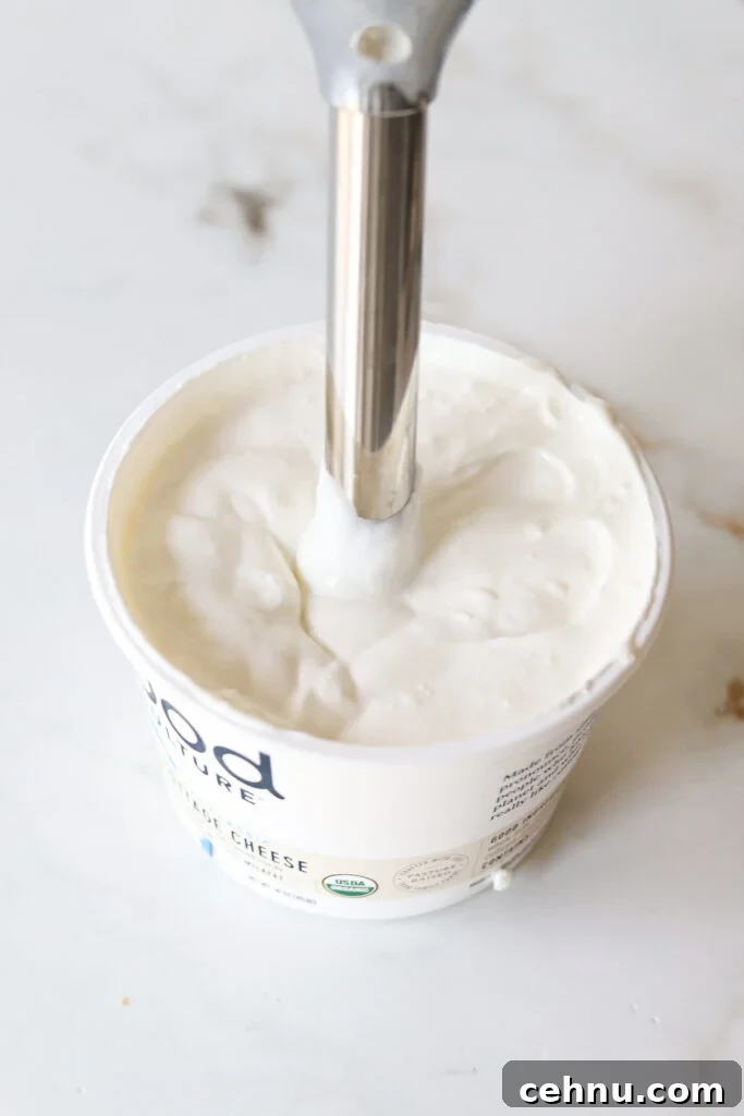 Cottage cheese being blended with an immersion blender.