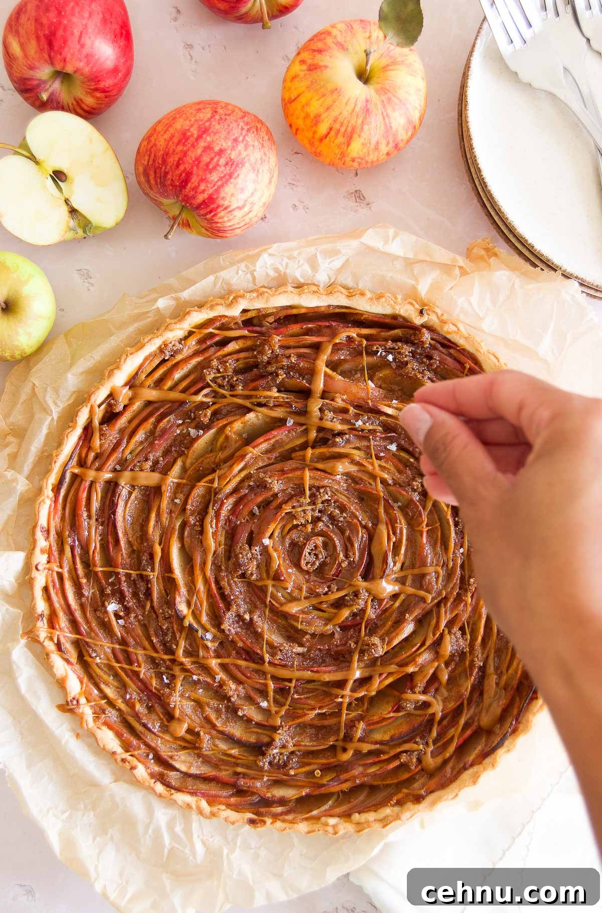 Apple Rose Tart with Dulce de Leche 7 a hand sprinkles large grain salt over a caramel apple tart
