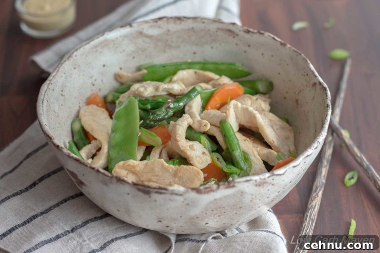 Chicken asparagus stir fry with carrots and snow peas in a bowl.