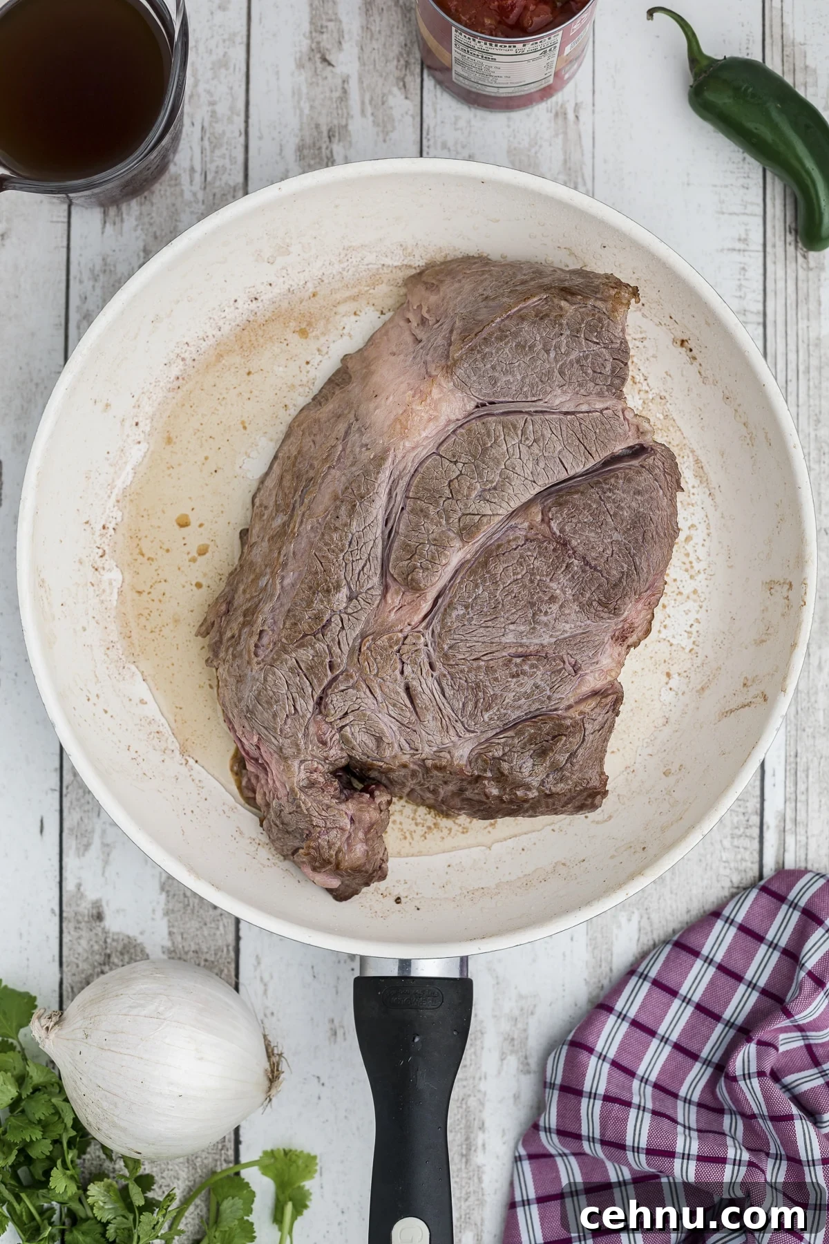 Chuck roast being browned in a skillet.