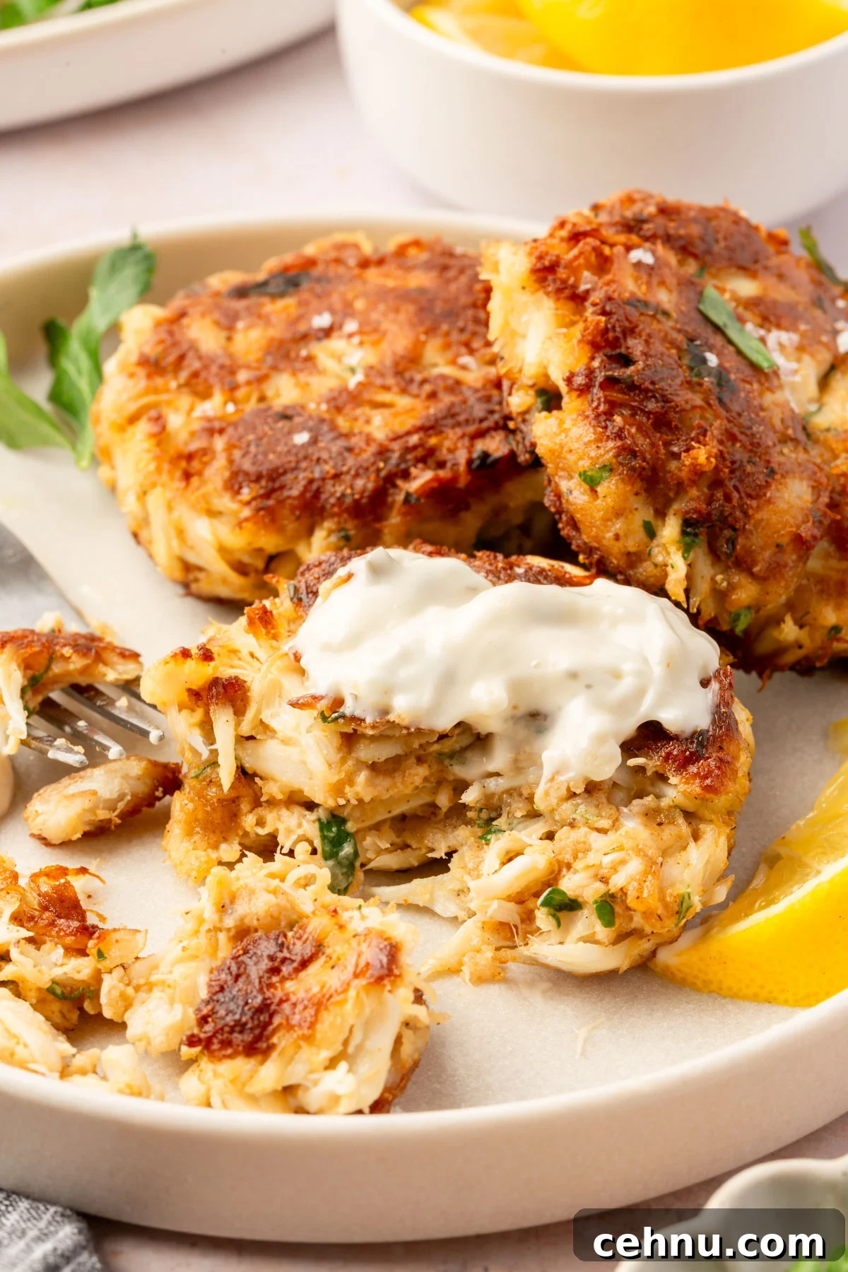 Crispy Gluten Free Crab Cakes Recipe with Lemon Dill Sauce 11 Gluten-free crab cake split open with tartar sauce on top and lemon wedge on the side