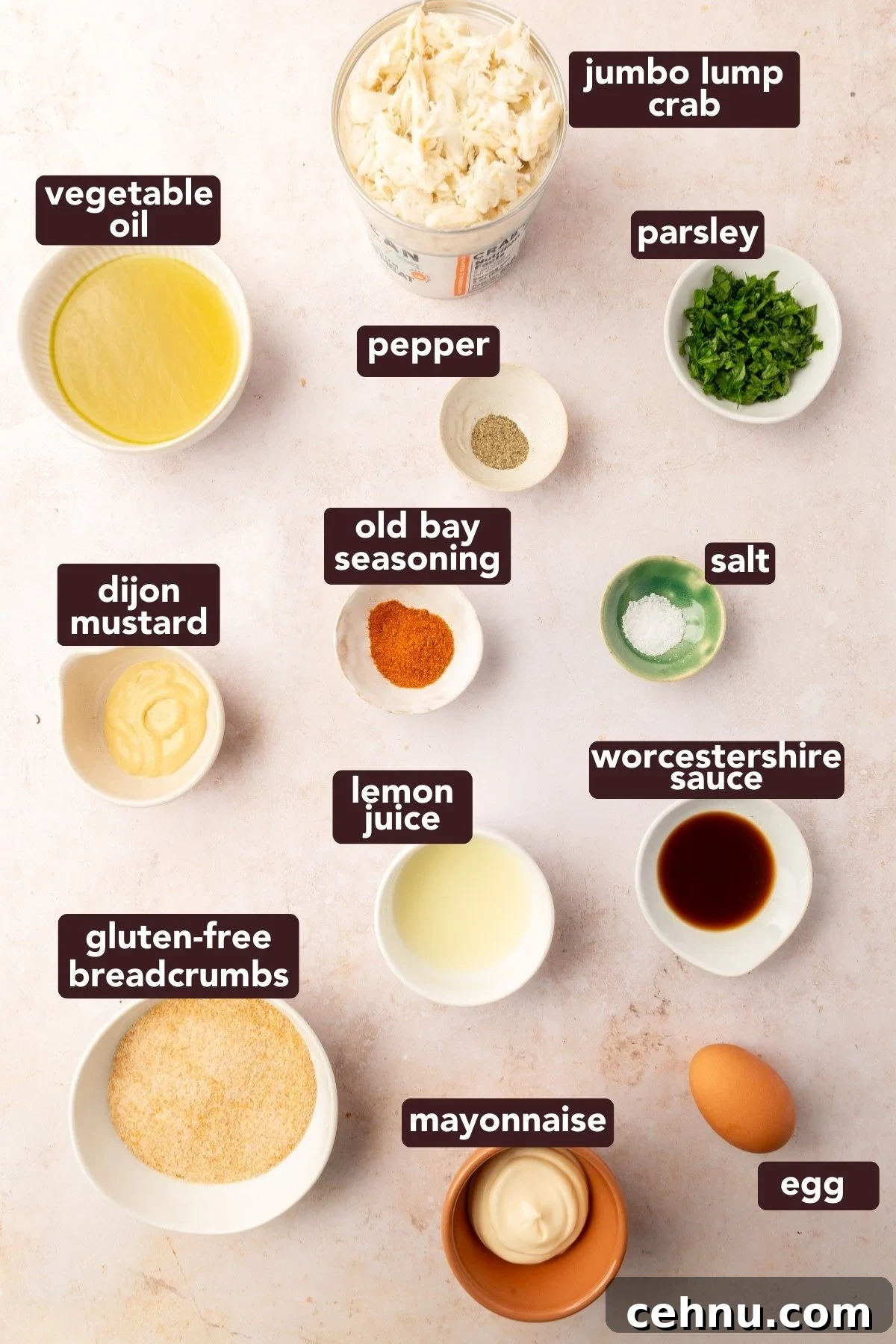 Crispy Gluten Free Crab Cakes Recipe with Lemon Dill Sauce 3 Overhead view of labeled ingredients for gluten-free crab cakes including jumbo lump crab, Old Bay seasoning, gluten-free breadcrumbs, and egg.
