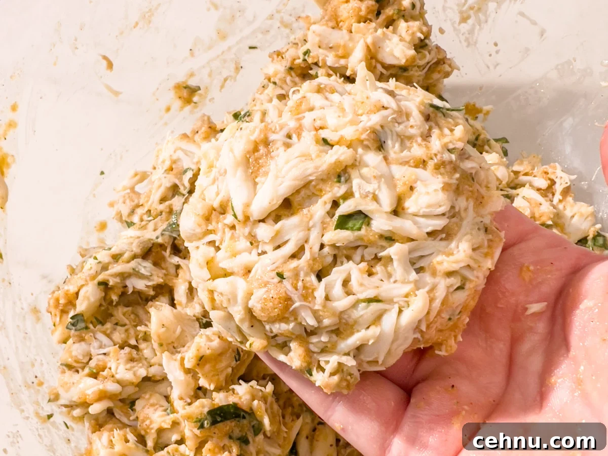 Crispy Gluten Free Crab Cakes Recipe with Lemon Dill Sauce 6 Uncooked gluten-free crab cake patty held in one hand before frying.