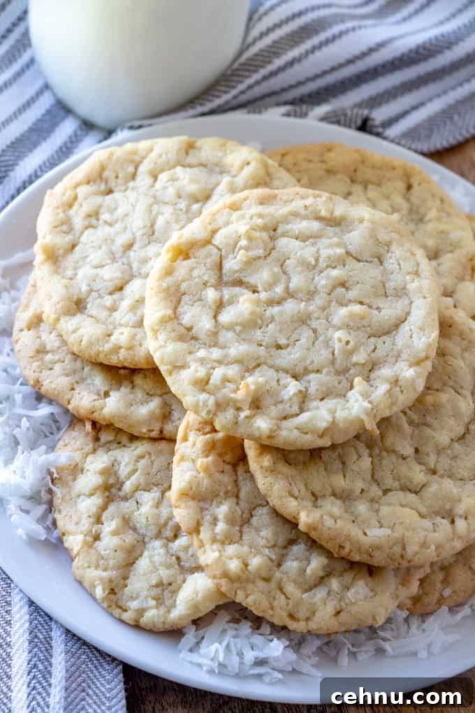 Coconut cookies stacked on plate with coconut shreds