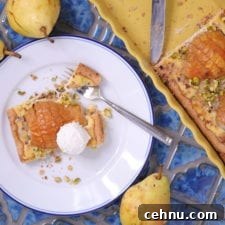 Piece of pear and frangipane tart on a plate with a fork.