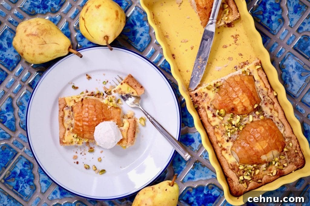 Piece of pear and frangipane tart on a plate with a fork.