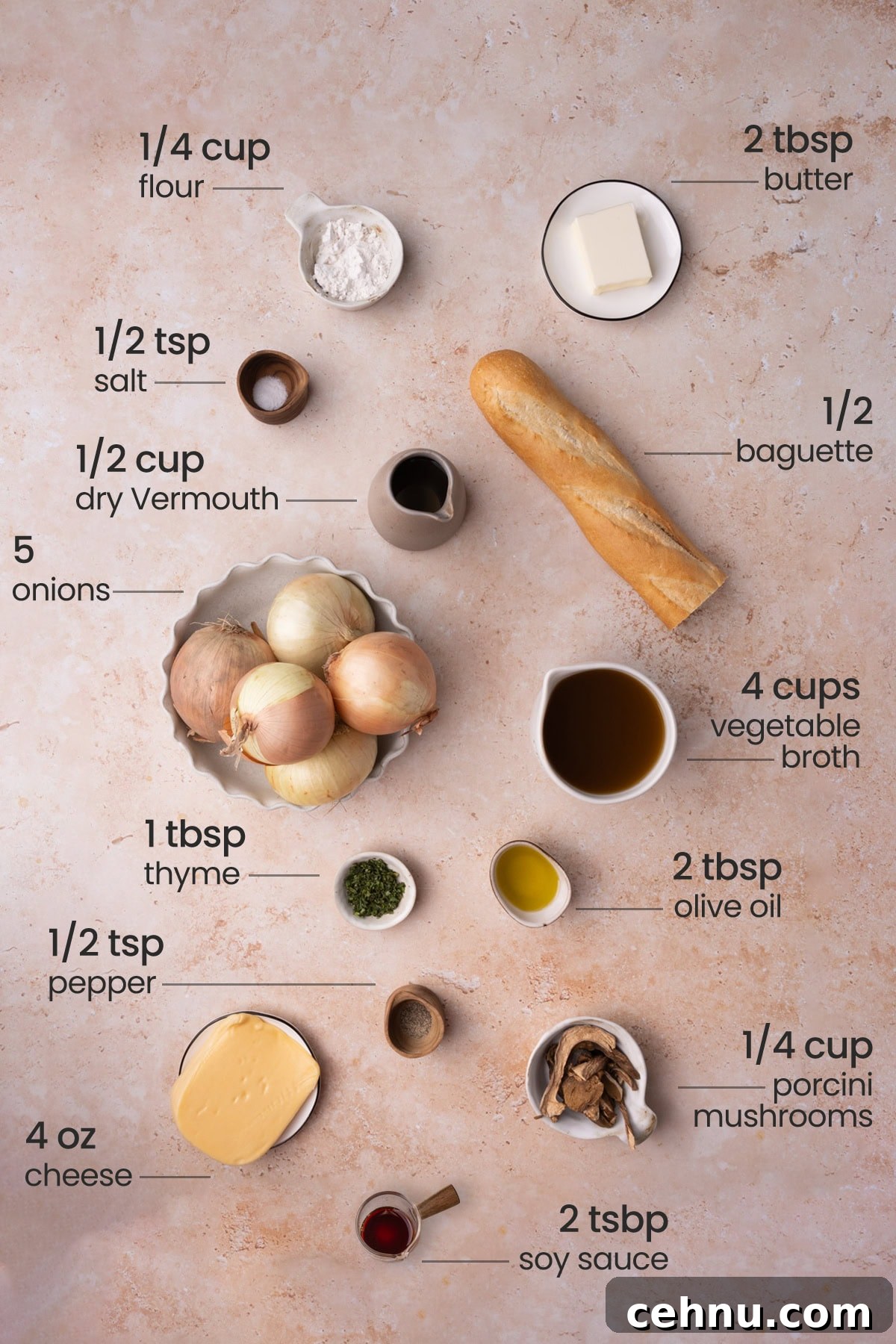 Overhead view of all the ingredients needed for vegetarian French Onion Soup - flour, butter, salt, dry vermouth, baguette, onions, vegetable broth, thyme, olive oil, pepper, cheese, porcini mushrooms, and soy sauce.