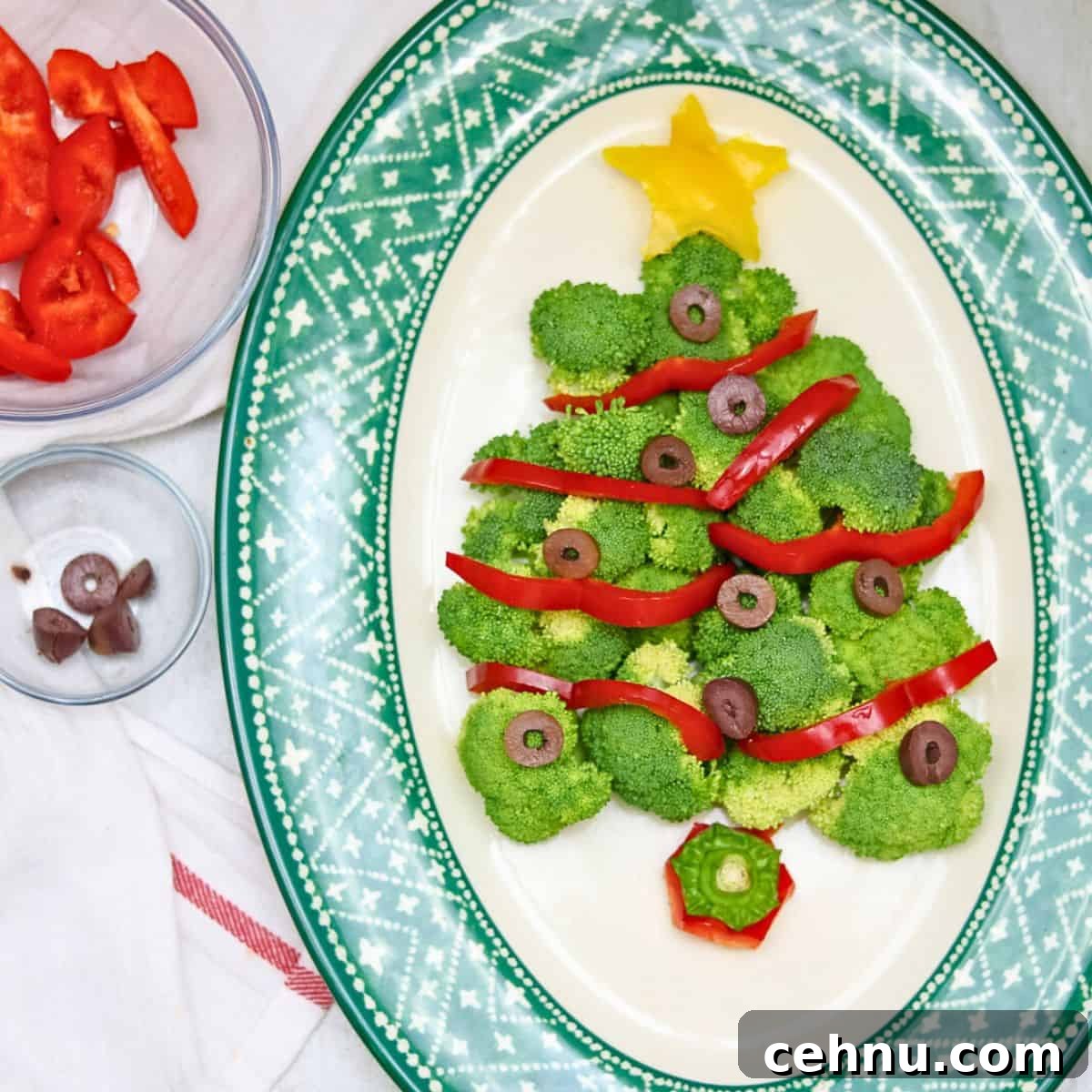 Christmas tree made with raw broccoli florets, red peppers, and black olive ornaments.