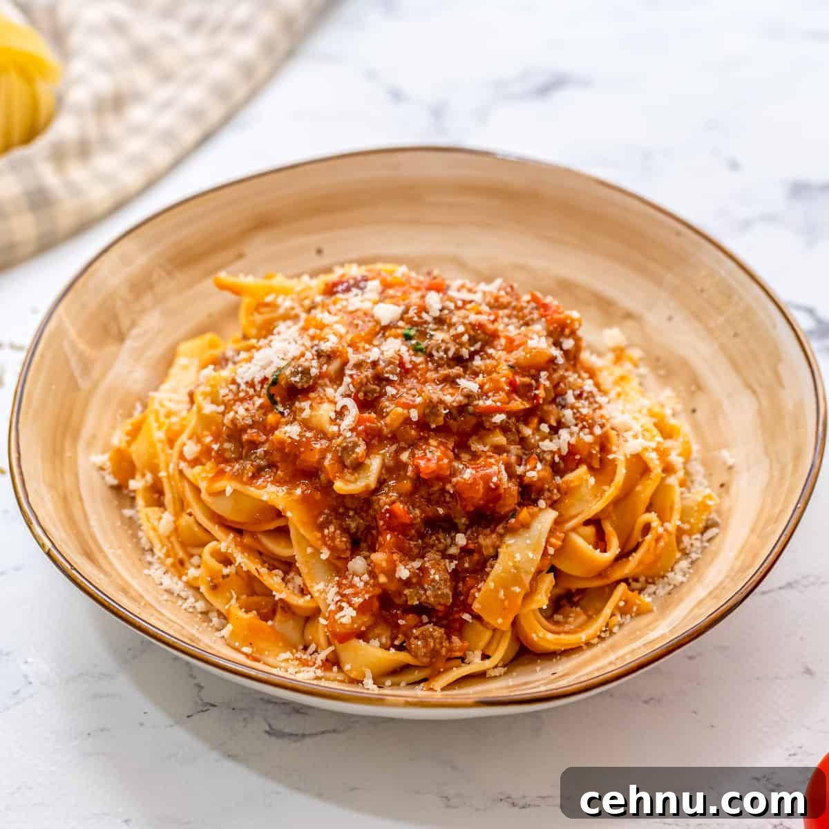 Pasta topped with bolognese sauce on cream plate.