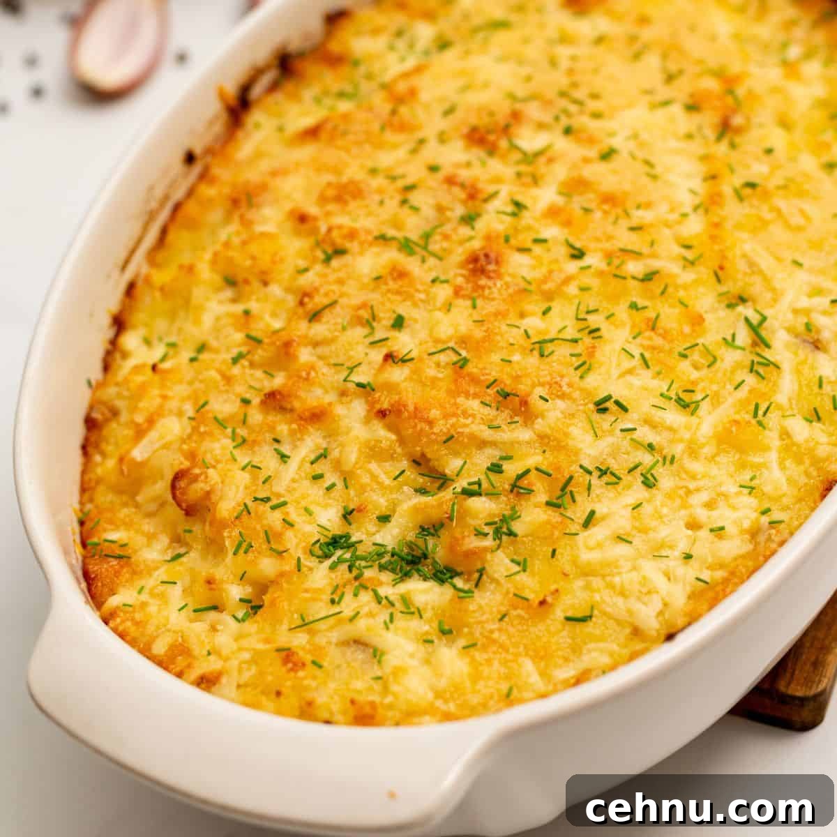 Baked Cheesy Potatoes Romanoff in casserole topped with minced chives.