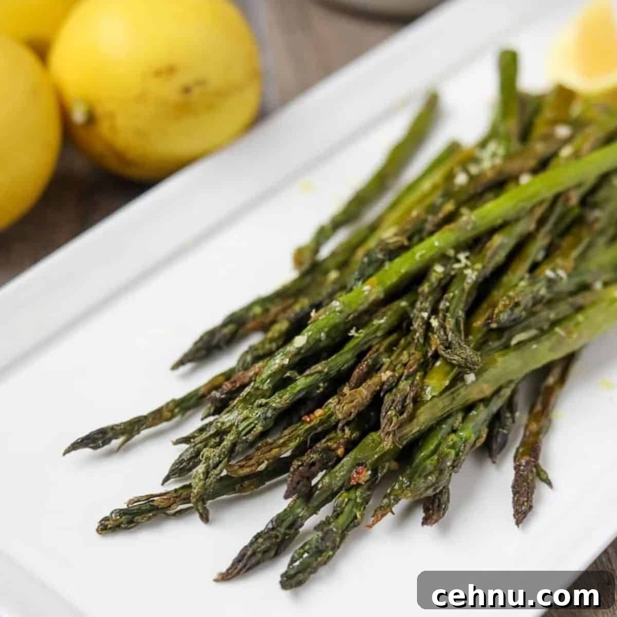 Roasted asparagus on white platter topped with freshly grated parmesan.