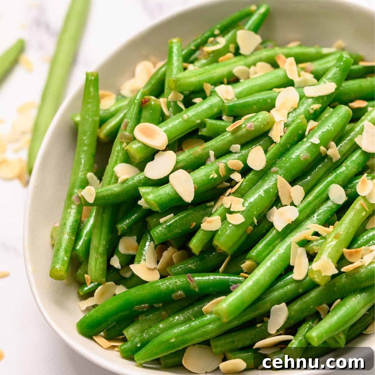Bowl of green beans almondine topped with slivered almonds.