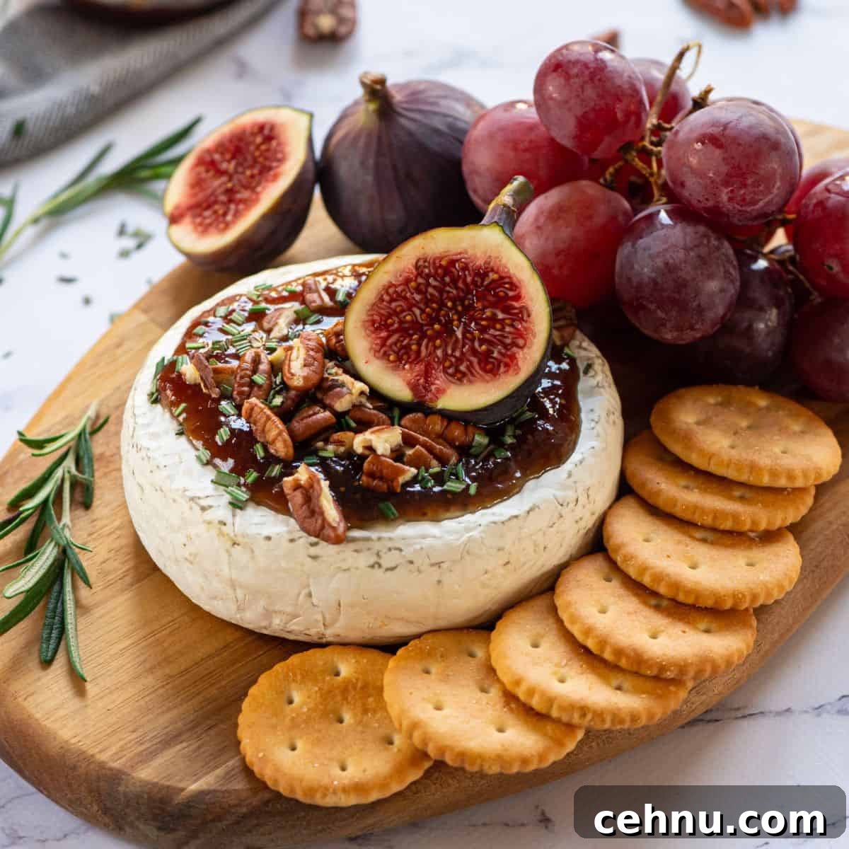 Baked Brie on cutting board topped with fig jam, walnuts, and fresh figs.