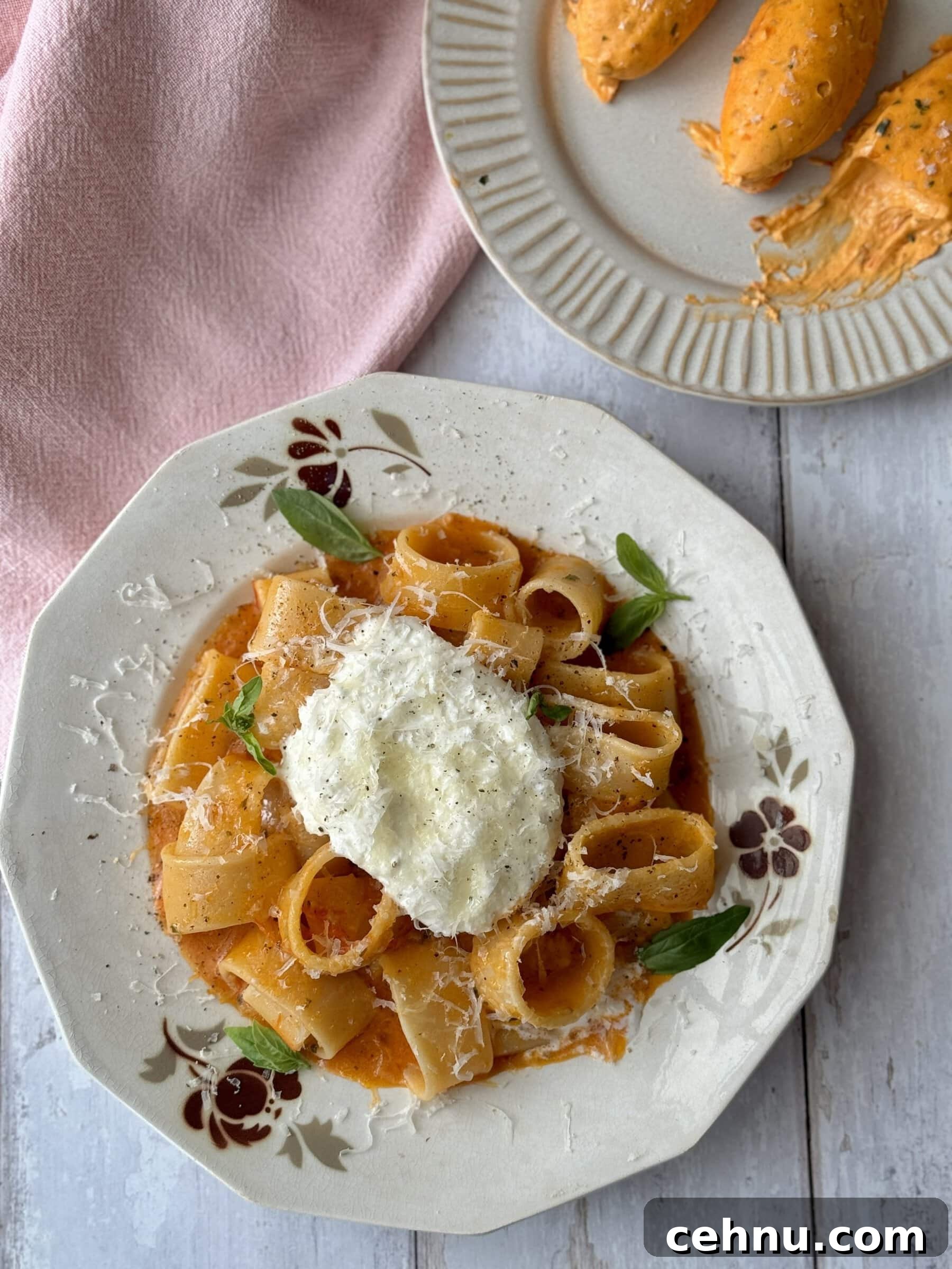 a white bowl filled with tomato butter pasta and topped with burrata